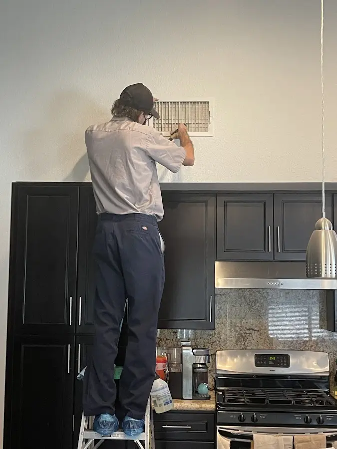 Technician inspecting an air vent during HVAC service in Delran